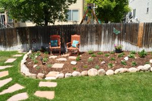 Garden planted and mulched with stone path and lawn chairs